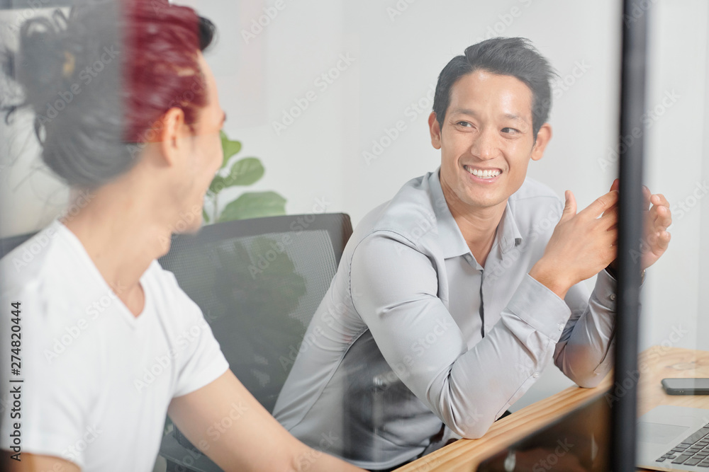 Fototapeta premium Cheerful young handsome businessman listening to idea of coworker at meeting