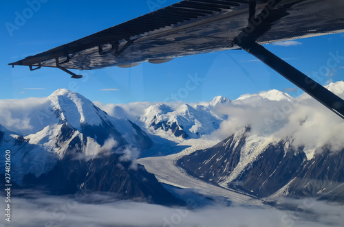 Aerial view of Alaska mountaion range around Denali peak from a plane with glaciers around and blue sky above. Denali National Park photo