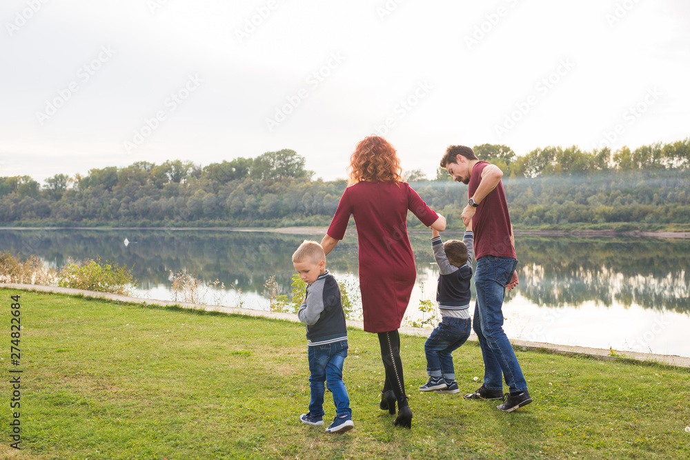 Parent, childhood and nature concept - Family playing with two sons by the water