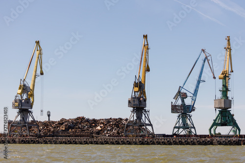 On the pier lies a large pile of metal scrap intended for loading into the vessel by using cranes