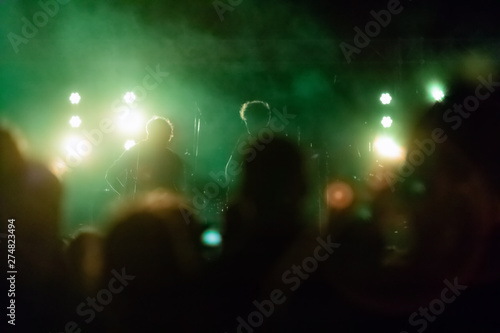 Fototapeta Naklejka Na Ścianę i Meble -  Silhouettes of musicians and audience in a concert with colorful smoke