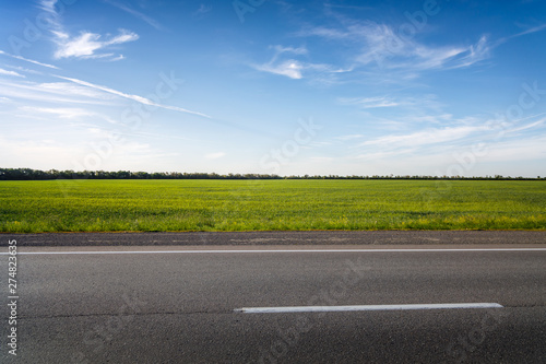 Empty asphalt highway against the bright sun at sunset