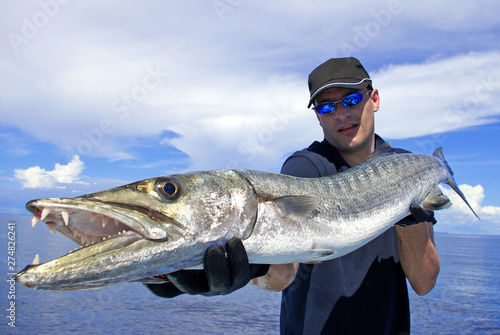 Deep sea fishing, catch of fish, big game fishing, fisherman holding a giant barracuda