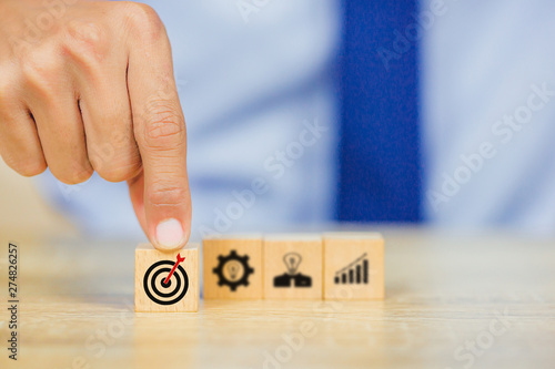 Hand of busines hold a target with arrow,stacking wooden blocks into steps,Concept of business growth success