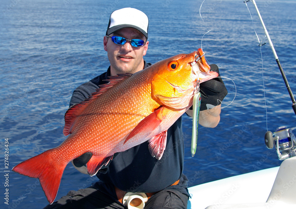fisherman holding a big red snapper fish, deep sea fishing, lure