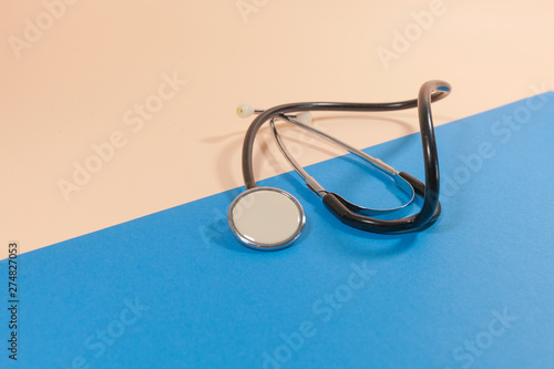 A stethoscope is laying on a pink and blue surface