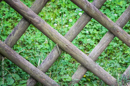 Diamond shaped wooden fence in green grass. The background.