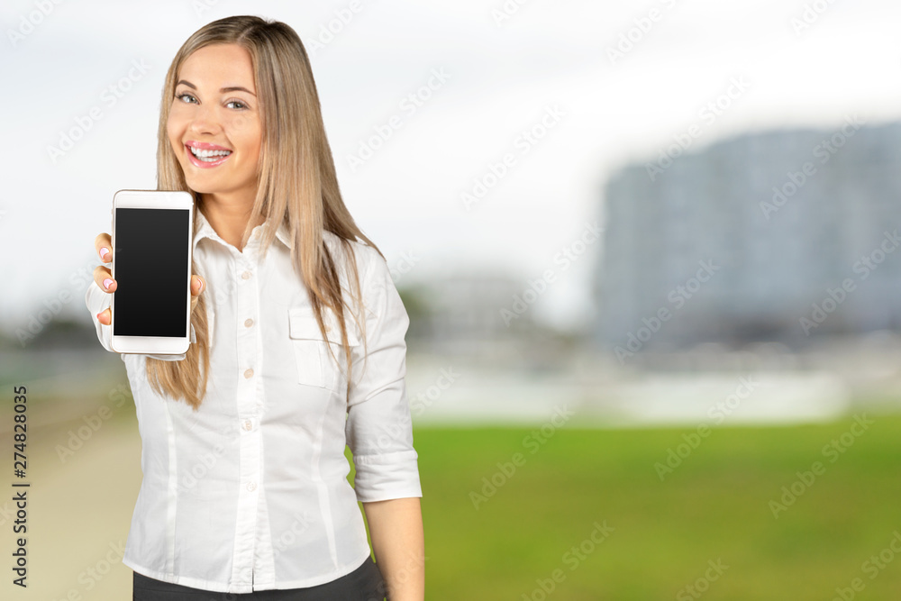 Fototapeta premium beautiful woman holding and showing white mobile phone with blank black screen