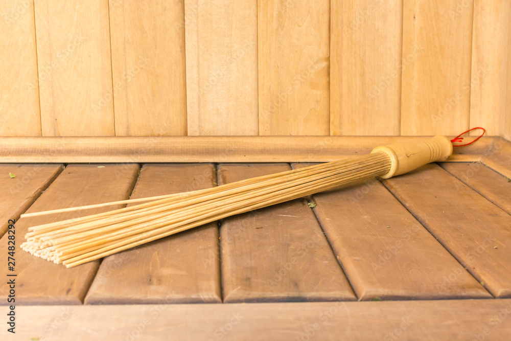 Bamboo broom lies on the shelf in the sauna