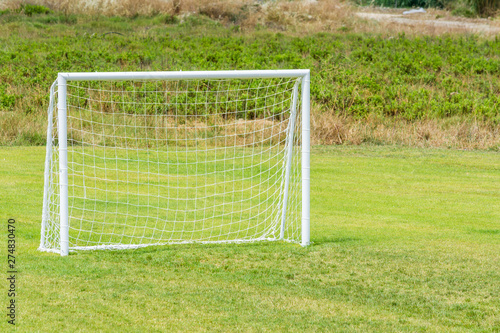 Football goal with net for playing on green grass.