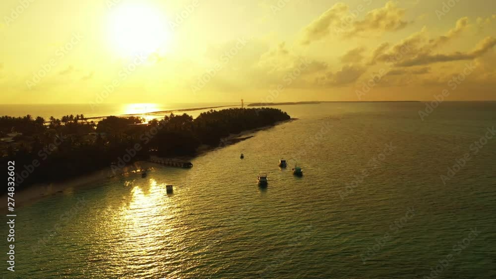 Aerial view of a tropical island with boats anchoring in front of it. During golden evening light before sunset. Dolly out Aerial view of a tropical island with boats anchoring in front of it. During golden evening light before sunset. Dolly out