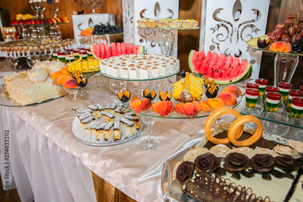 Candy bar at the wedding reception. Cakes, sweets and fruit on the table.