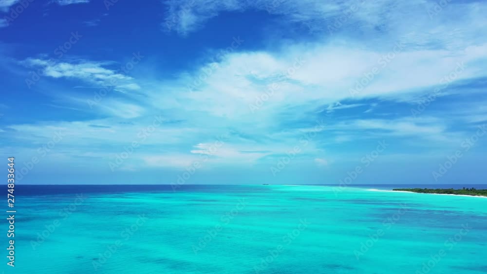 Aerial view of the turquoise Philippine Sea under a cloudy blue sky. With an island on the left. Aerial view of the turquoise Philippine Sea under a cloudy blue sky. With an island on the left.
