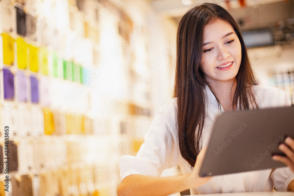 Smiling Asian business woman looking tablet stay material room .young Asian business executive happy. Smiling Asian business woman looking tablet stay material room .young Asian business executive happy.