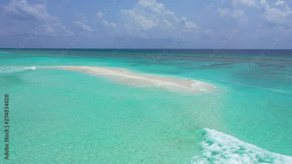 Aerial view of a sandbank in turquoise water with some waves breaking on it. In the Maldives, circular movement. Aerial view of a sandbank in turquoise water with some waves breaking on it. In the Maldives, circular movement.