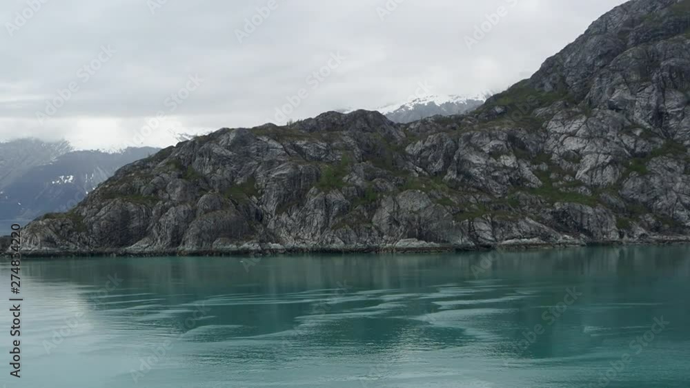 Cruising around Glacier Bay, Alaska in May 2019. Rocky shores, mossy cliffs, and snow capped mountains. Cruising around Glacier Bay, Alaska in May 2019. Rocky shores, mossy cliffs, and snow capped mountains.