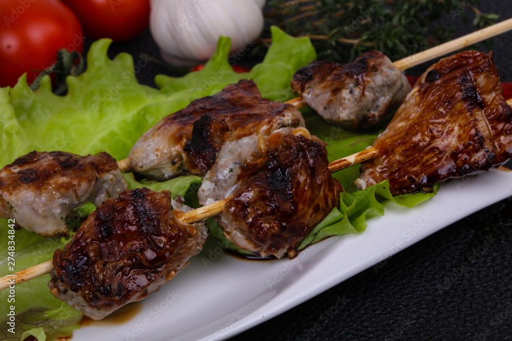 Pork kebab skewers in the plate with salad leaves and tomatoes Pork kebab skewers in the plate with salad leaves and tomatoes