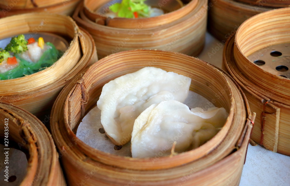 Close up Chinese gyoza steamed dumplings in bamboo basket in dim sum set Close up Chinese gyoza steamed dumplings in bamboo basket in dim sum set