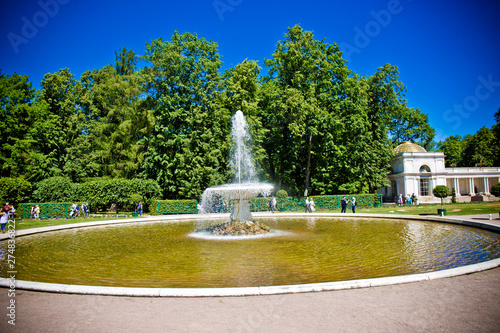 fountain on the lake on a background of green park under a blue sky