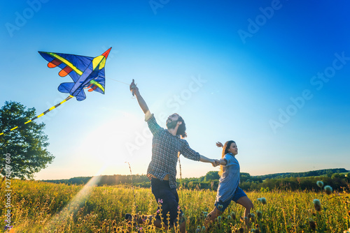young happy beautiful couple flying a kite in a summer field, summer happiness and love concept