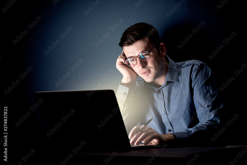 Young handsome businessman working late at night in the office with a dark background Young handsome businessman working late at night in the office with a dark background