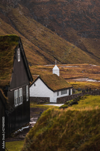 Saksun church / Saksunar kirkja as spotted during spring from within Saksun with snow-covered mountain ranges in the background (Faroe Islands, Denmark, Europe) photo