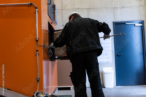 Chimney sweep cleaning a chimney standing balanced on the apex of a house roof lowering equipment down the flue