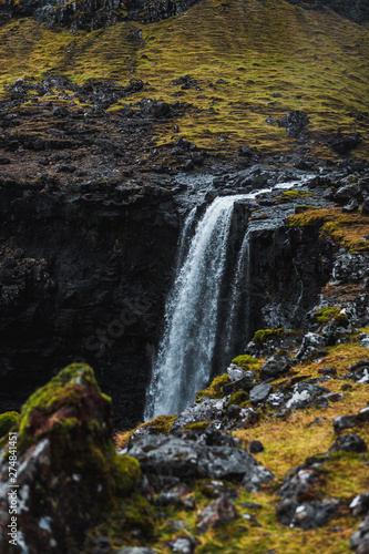 Fossa, the largest waterfall on the Faroe Islands, as seen during early spring with snow-covered mountain peaks and lush greens (Faroe Islands, Denmark, Europe) 