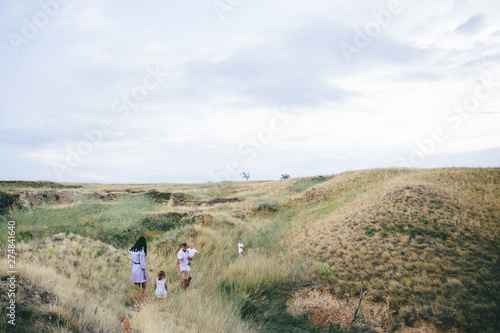 Happy parents and children are walking outdoors in a wheat field view.