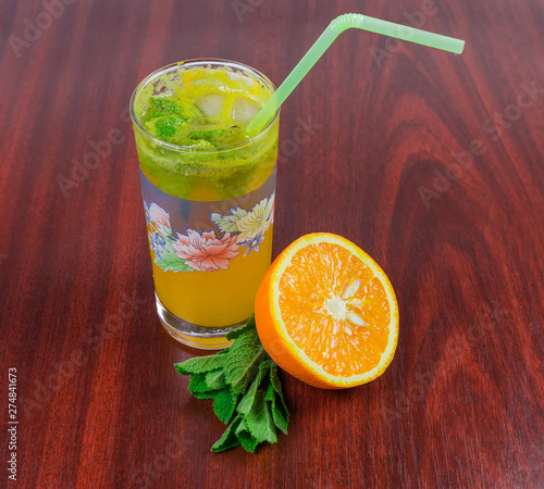 Cold orange drink, mint, half of orange on wooden table photo