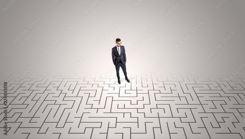 Elegant businessman looking for a solution in a middle of a maze
Elegant businessman looking for a solution in a middle of a maze