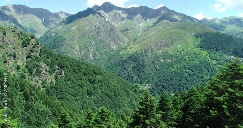 Flying over valleys, meadows, forests and small villages in the Alps. Aerial view of the Valsesia, Piedmont, Italy