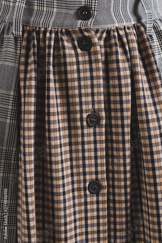Plaid dress on buttons combined with two different types of cloth. Vertical background. © Alexander