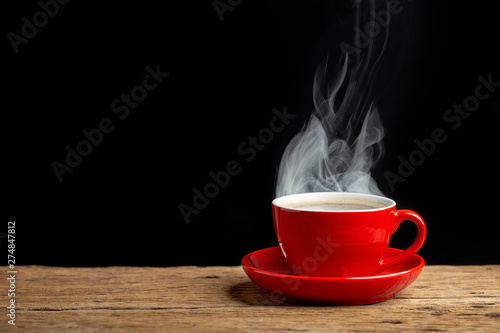 hot coffee in red cup on old wooden table with black wall background.