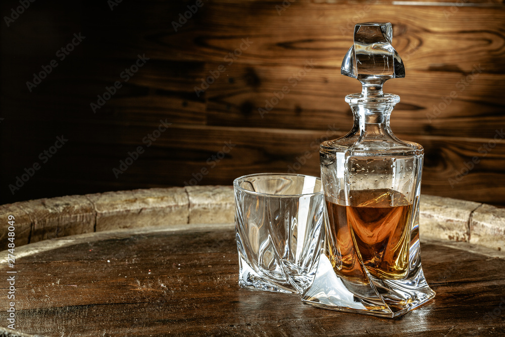 A bottle of cognac and glass on a brown wooden background. Brandy A bottle of cognac and glass on a brown wooden background. Brandy