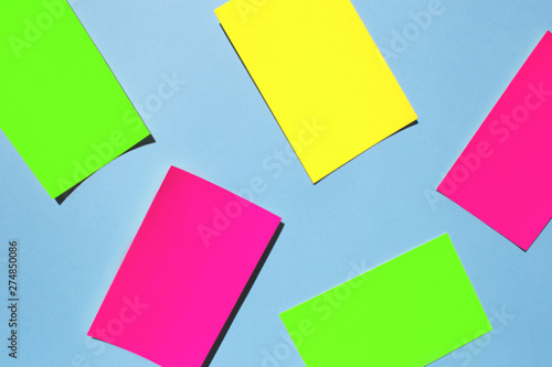 Neon colorful sticky note paper on blue background. Copy space for your text. Flat lay, top view. 