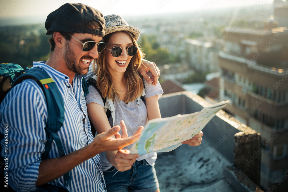 Young couple travelling with a map in the city - obrazy, fototapety, plakaty 