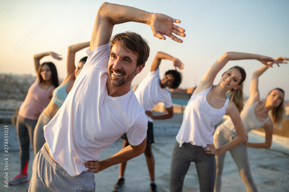 Group of fit healthy friends, people exercising together outdoor on rooftop - obrazy, fototapety, plakaty 
