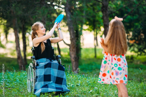 A young disabled girl plays Frisbee with her younger sister. Interaction of a healthy person with a disabled person