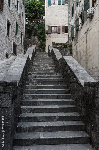 Ancient stairs in Old town Kotor. Medieval stone staircase between apartment buildings in the old town center of Montenegro. Cats in the street waiting for food in a wall © Baifoworld