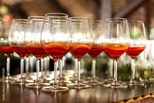 A lot of cocktails at the bar at the wedding party. Glasses with apperol and with a slice of lemon close-up © Kate