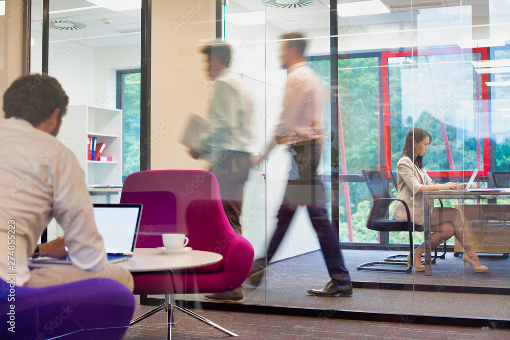 A working office with people walking out of focus, concept of a real life busy office environment A working office with people walking out of focus, concept of a real life busy office environment