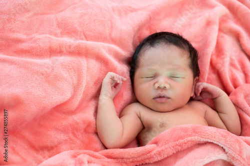 Newborn baby girl sleeping in pink cloth.