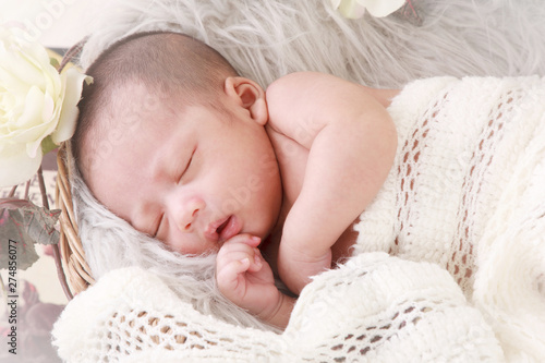 Adorable asian newborn baby in wrap sleeping on white blanket background. Portrait of newborn boy sleep on bed. Close eyes.
