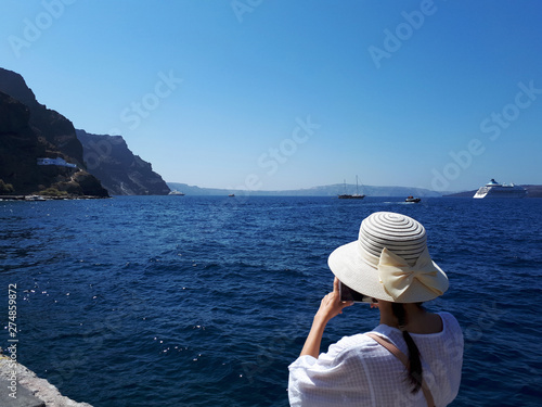 Beautiful woman taking pictures on the phone in Santorini, Greece