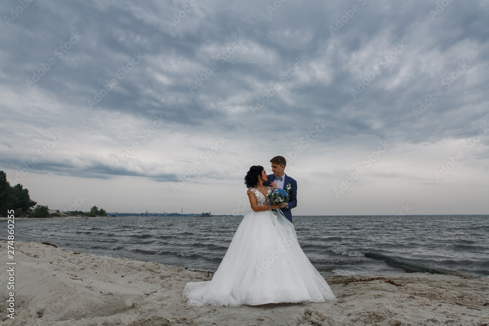 stylish brides walking on the sandy beach. groom hugging bride and walking on beach.wedding day. wedding walks.stylish couple in love stylish brides walking on the sandy beach. groom hugging bride and walking on beach.wedding day. wedding walks.stylish couple in love