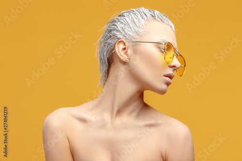 Young sexy girl with white dyed hair and creative make-up poses in yellow sunglasses