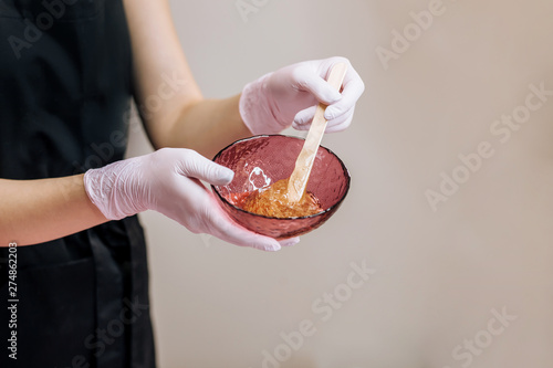 cosmetologist holding jar with wax for depilation