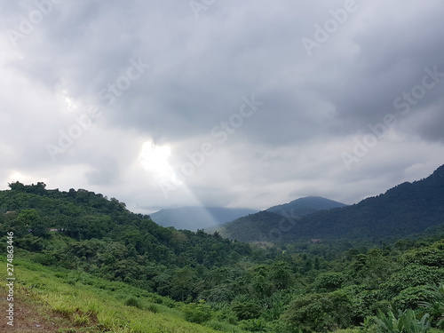 Light beam passes through clouds shining over a tropical valley