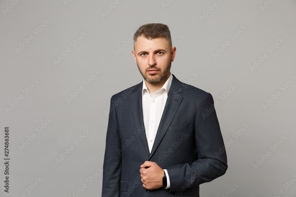 Handsome successful confident young business man in classic black suit shirt posing isolated on grey wall background, studio portrait. Achievement career wealth business concept. Mock up copy space. - obrazy, fototapety, plakaty 